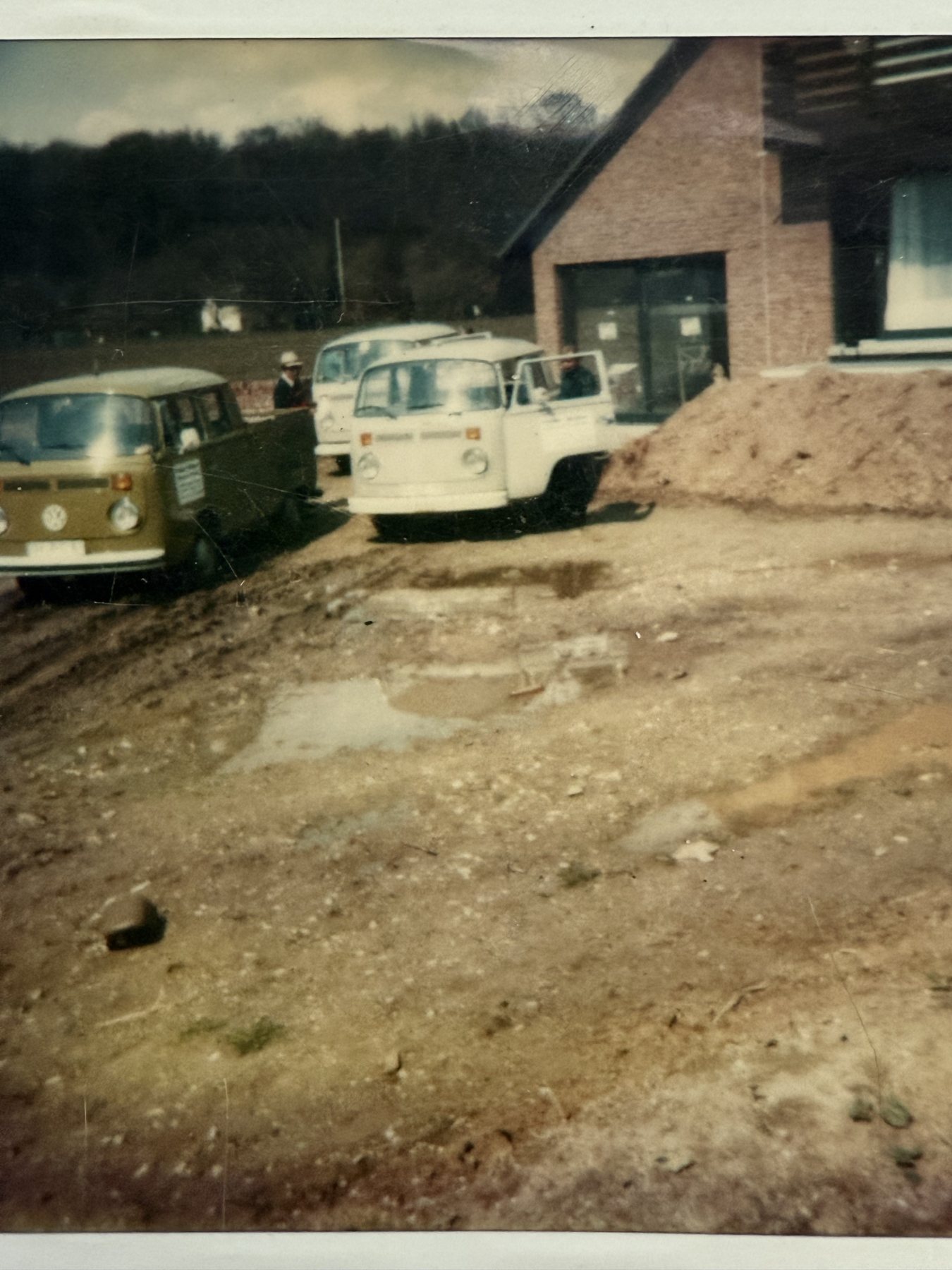 Historische Fahrzeuge des Maurerbetriebs vor einer Baustelle